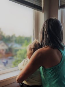 Woman holding baby looking out window