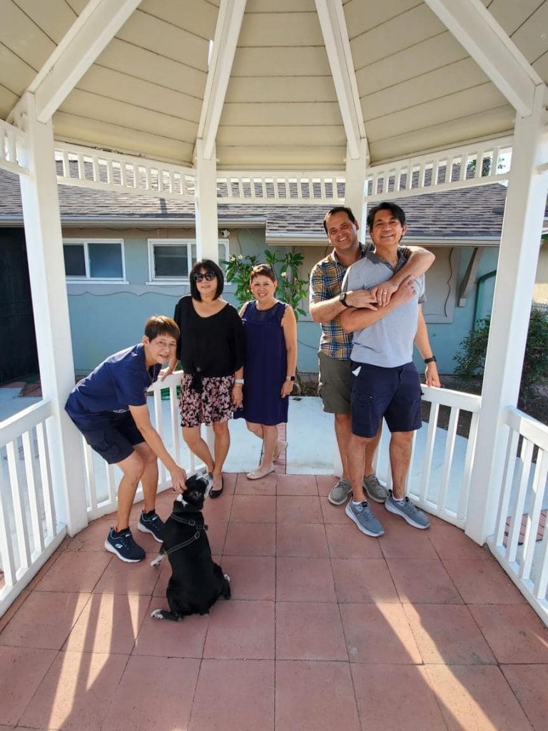 Five people standing in a gazebo in the front yard of a house