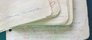 Bottom edges of a stack of lined paper with handwritten text