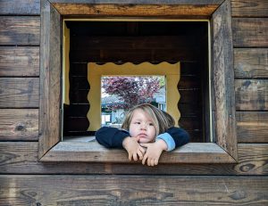Toddler leaning out a playhouse window