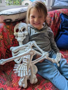 Smiling toddler sitting next to skeleton