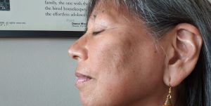 Profile of brown woman, eyes closed, with focus on ear.