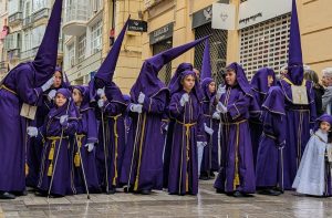 Children and adults dressed in purple hoods and robes during Holy Week in Malaga, Spain