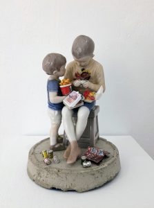 Figurines of two boys to which items of junk food are attached