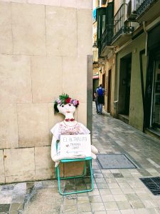 Large Mexican cloth doll on a chair with a store sign