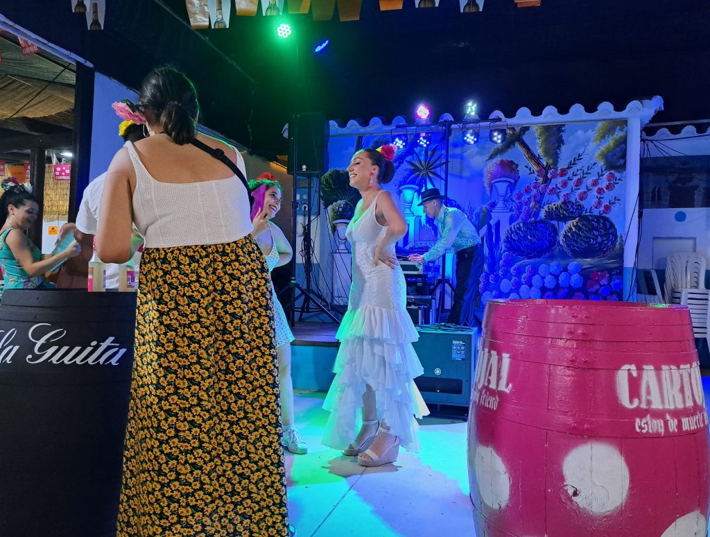 Women in Flamenco dresses and a DJ in background in a disco-setting