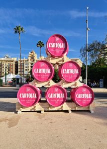 Five pink barrels of wine stacked in a pyramid on a plaza in Malaga