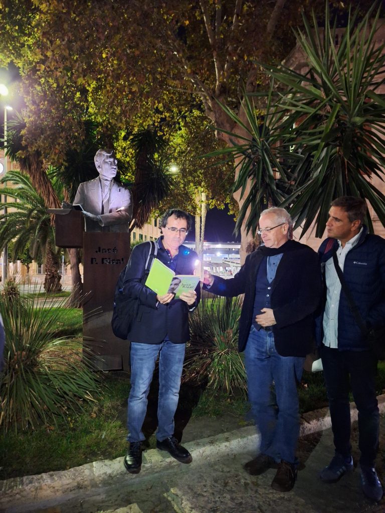 Man reading a poem in front of statue of Jose Rizal in Malaga at night
