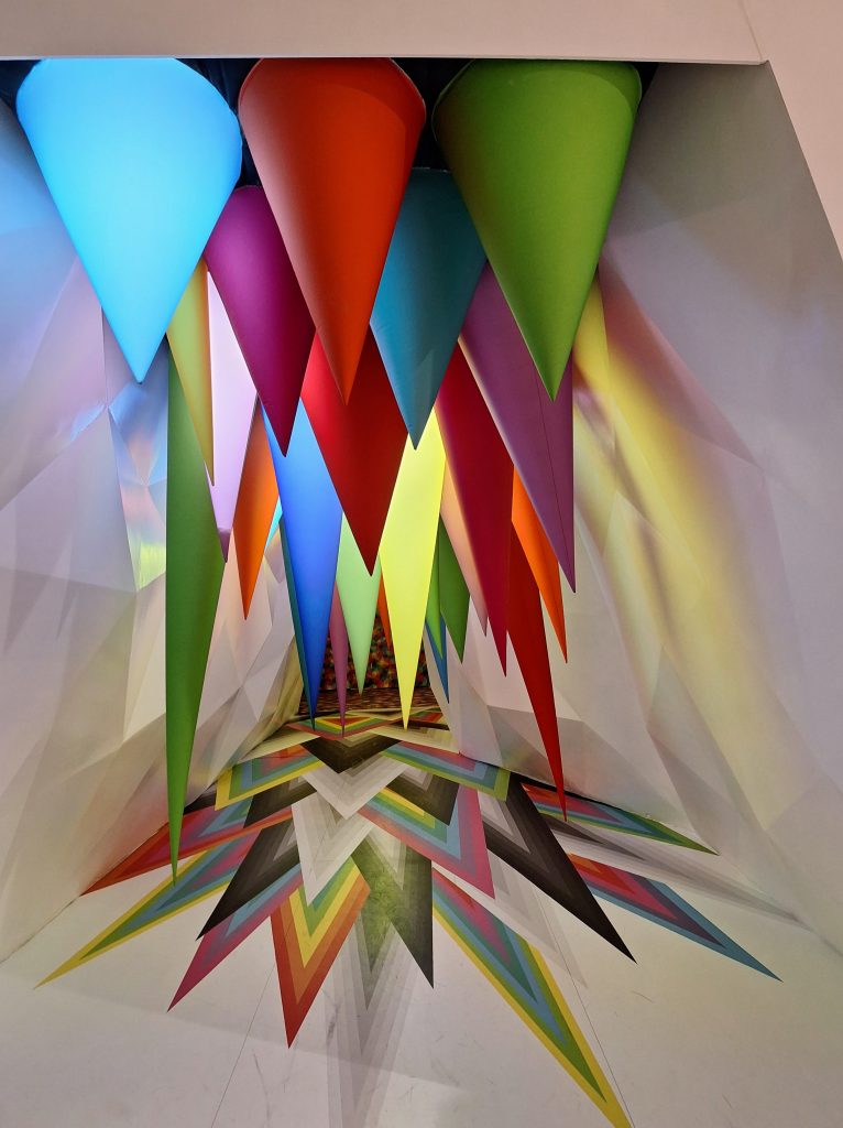 Colorful conical shapes hung from the ceiling at an art gallery
