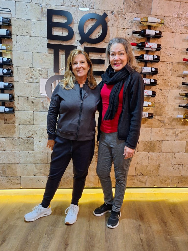 Two women standing in front of a wall of wines on display