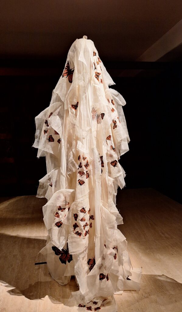 Art oiece consisting of white flowing fabric with monarch butterflies attached.