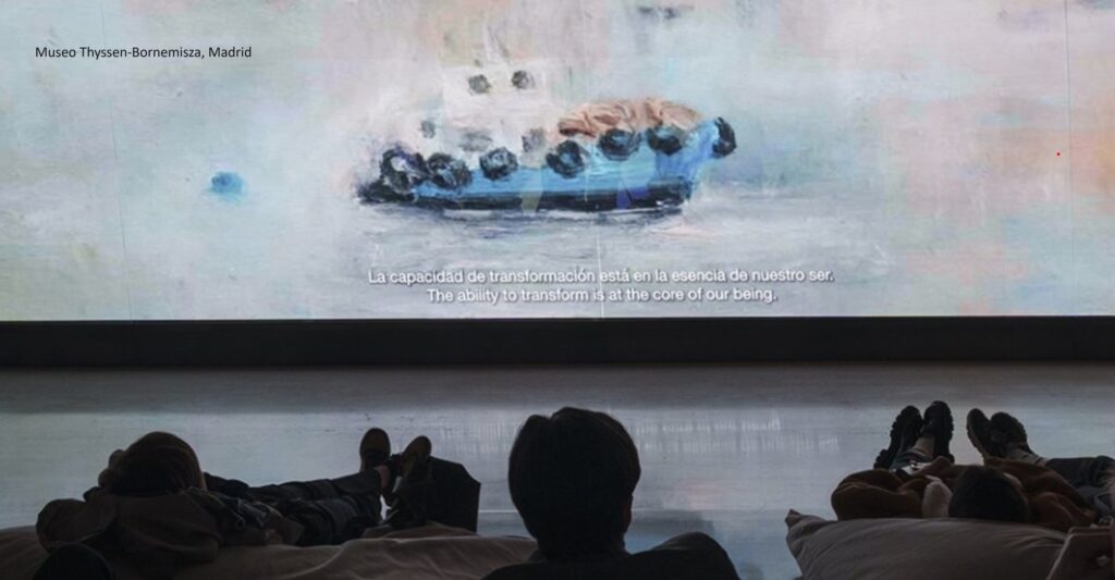 Painting of a boat on a screen in a small theater with viewers seated on pillows