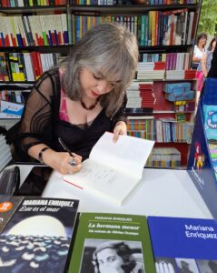 Woman signing books in a bookfair booth.