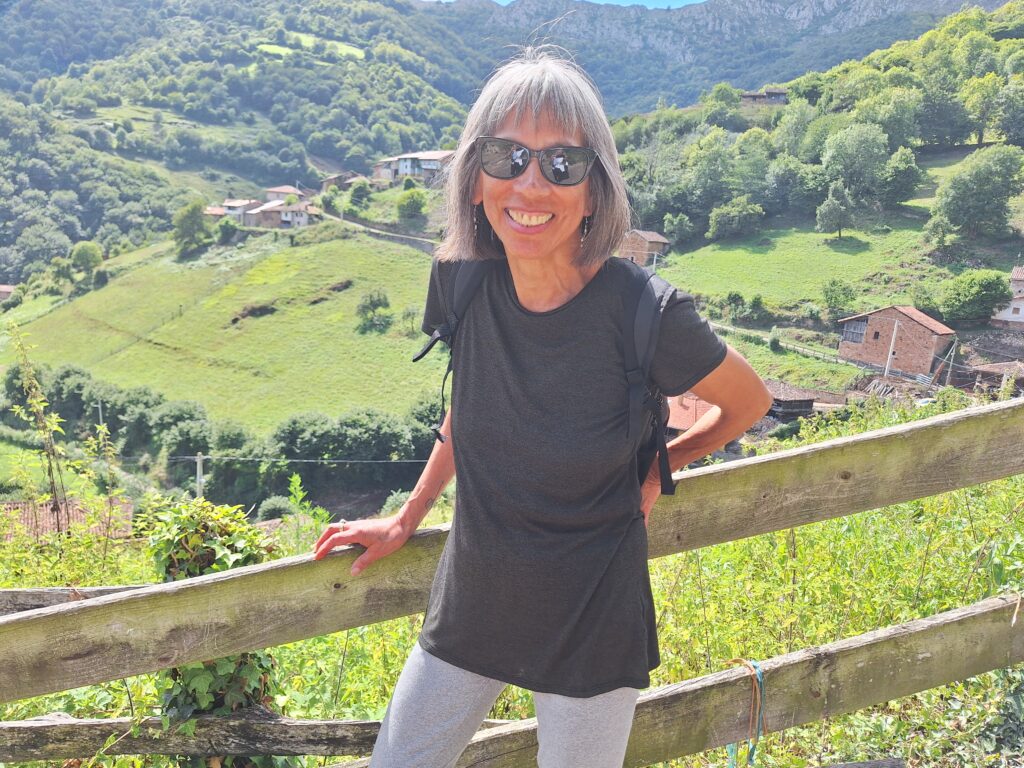 Woman standing against fence with green mountainscape in the background in Asturias, Spain