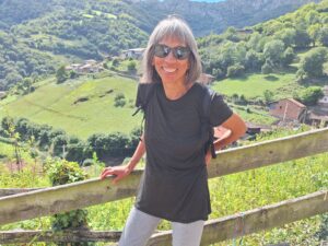 Woman standing against fence with green mountainscape in the background in Asturias, Spain