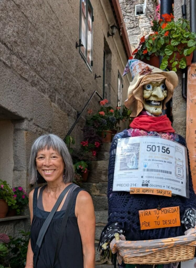 Woman standing next to a life-size figure of a witch in Combarro, Spain