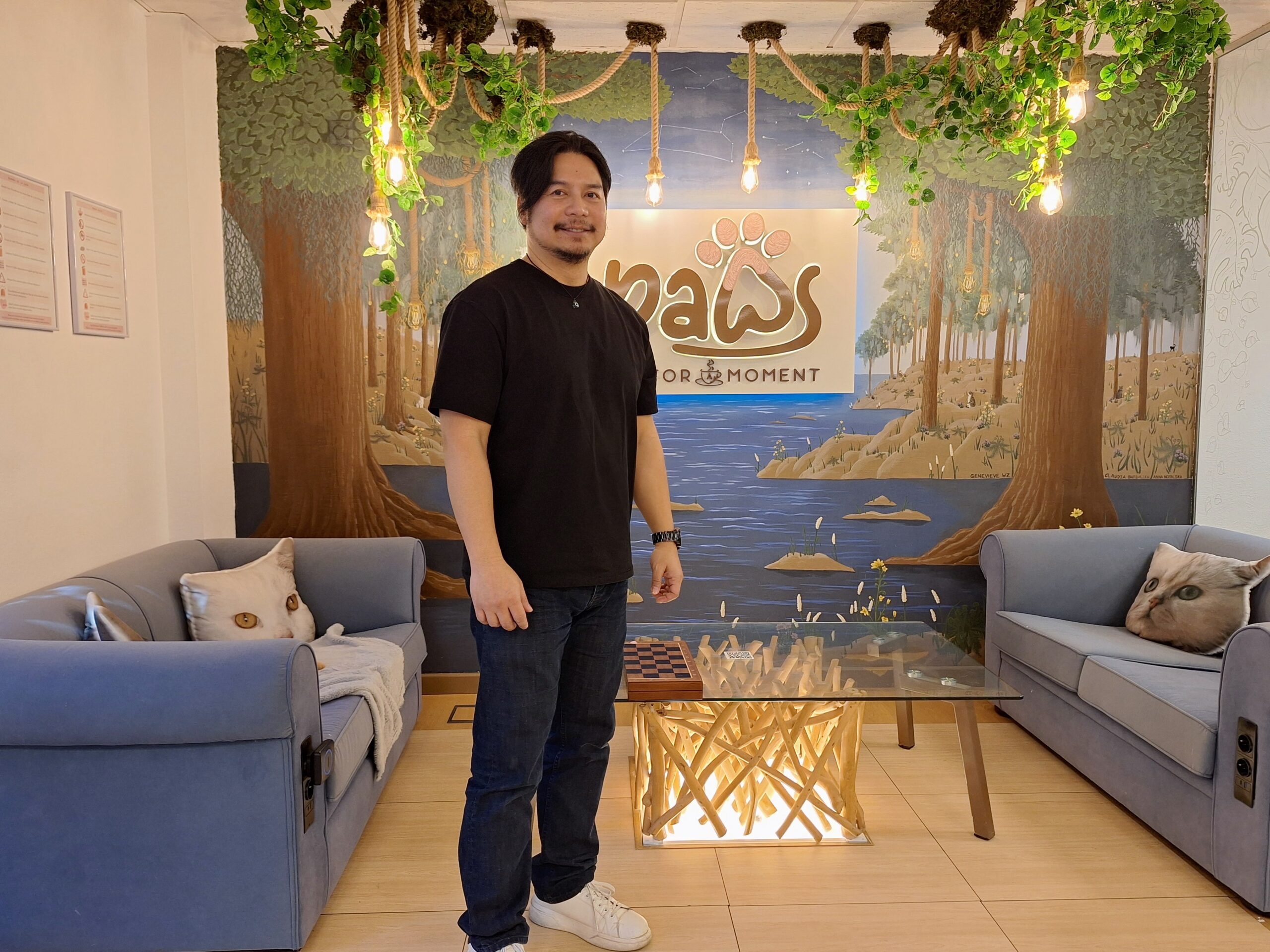 Filipino American man standing in the lounge area of his cat cafe and co-working space in Malaga, Spain