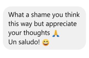 Screen shot of a message that reads, "What a shame you think this way but appreciate your thoughts," followed by a praying hands icon, followed by "Un saludo!" followed by a grinning face icon