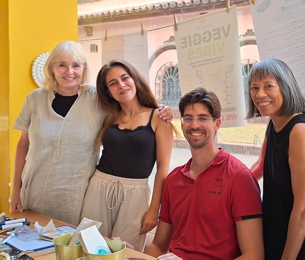Three women and a man in front of a window of a cafe facing the camera