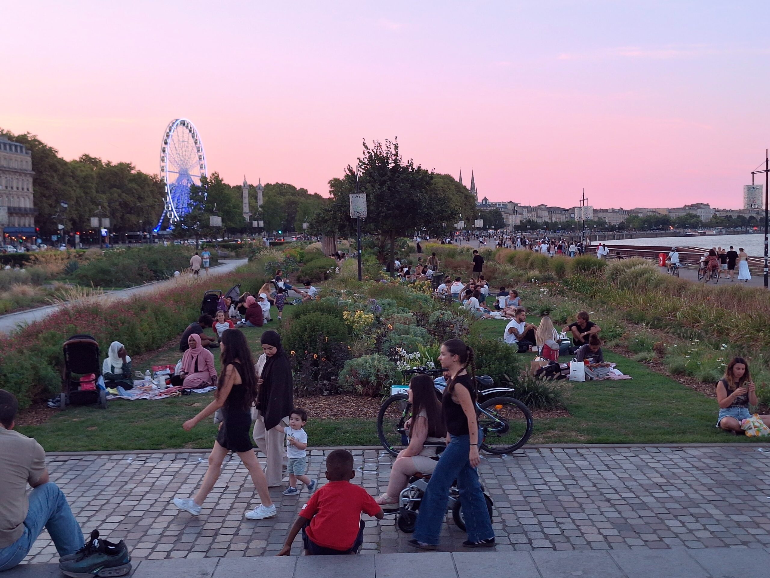Riverside view in Bayonne, France with picnickers on the lawn and the ferris wheel in the background