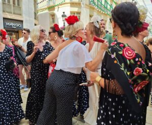 Women dressed for feria in Malaga, Spain: black dresses with white polka dots ad red flowers in their hair.