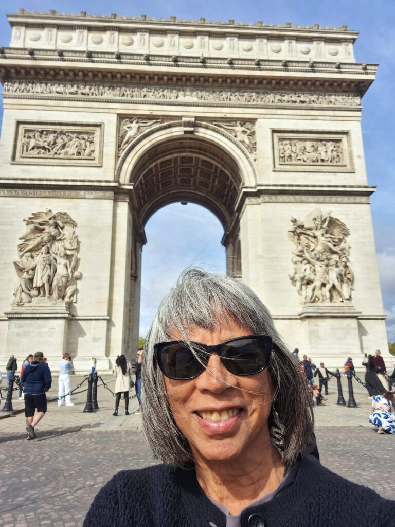 Headshot of a woman standing in front of the Arc de Triomphe in Paris