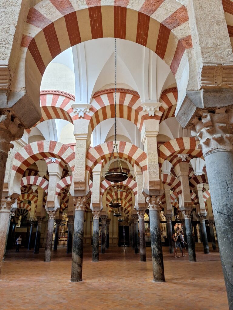 View of pink and white striped arches inside the Great Mosque of Cordoba, Spain.