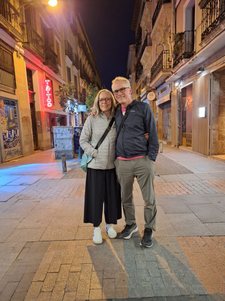A man and woman in jackets on a street in the Barrio de las Letras at night in Madrid