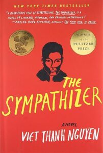 Book cover for The Sympathizer by Viet Thanh Nguyen. Red backgrouond with yellow title and white author name. Drawing of man's face in the center in black. Two gold seals indicating awards flank the head.