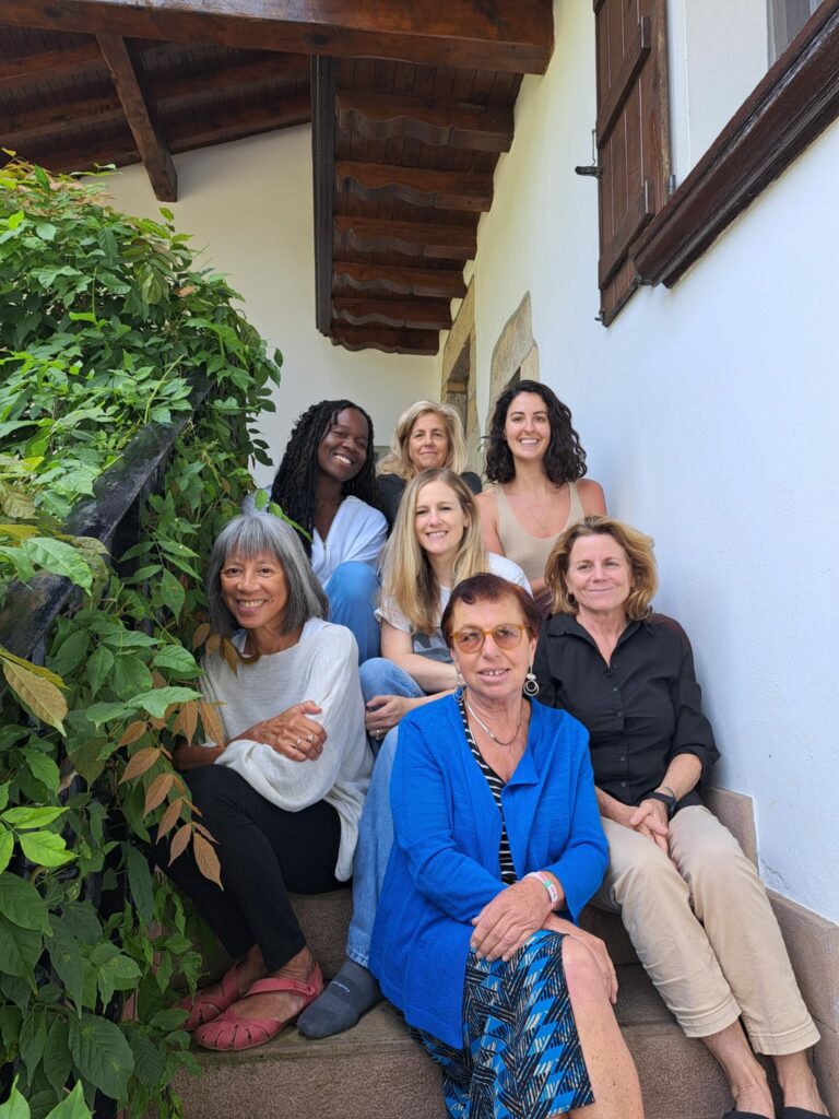 Seven women seated on the steps of a white-washed house in the Basque Pyrenees.