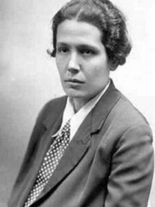 Black and white, three-quarter portrait of stern-faced woman with short hair from the 1930s. Shre's dressed in a white shirt, polka-dot tie and blazer.