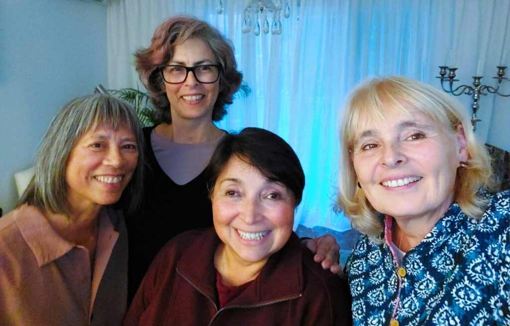 headshots of four smiling women with white drapes in the background.