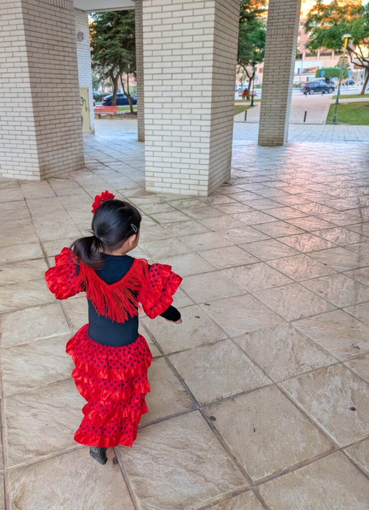 A little girl dressed in Flamenco attire scampers through a plaza.