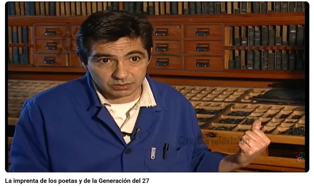 A man in a blue shirt is in front of shelves and drawers in a print shop.