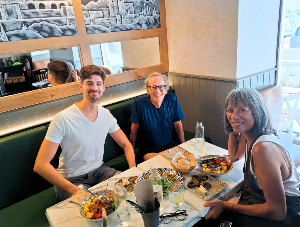 Two men and a woman seated at a restaurant with food on the table