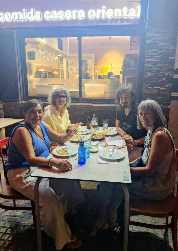 Three women and a man sitting at a table on the terrace of a Chinese restaurant at night.